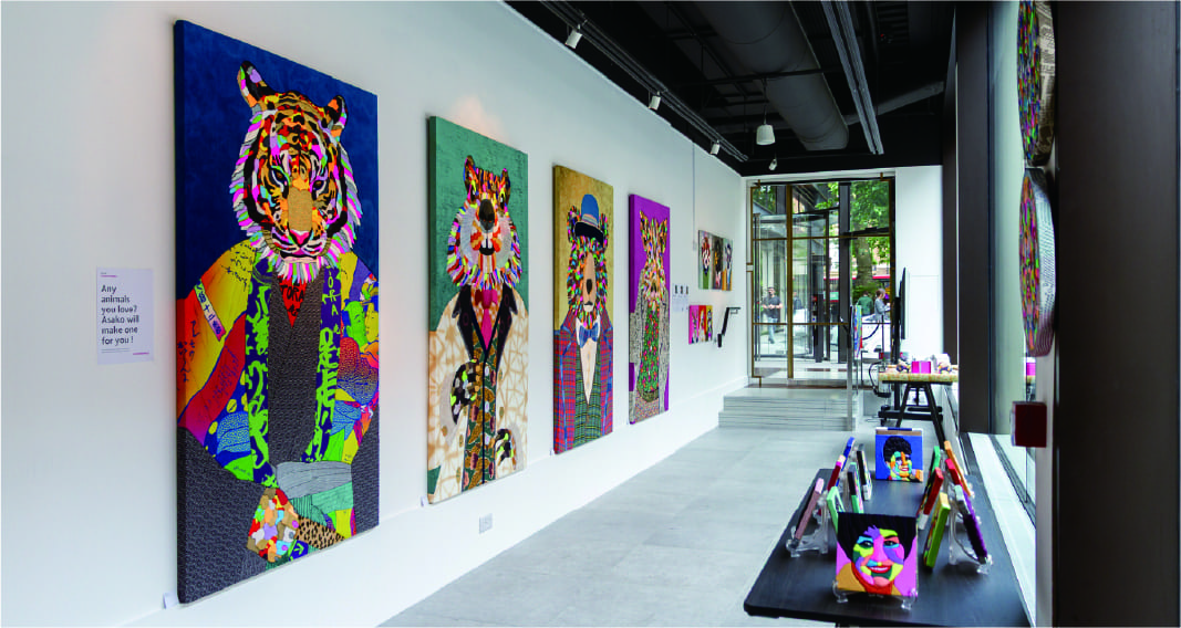 白いギャラリー空間に並ぶカラフルなアート作品の展示風景